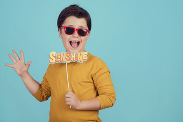 sunshine,niño gracioso con gafas de sol sobre fondo azul