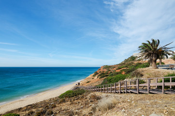 Fototapeta na wymiar Wooden stairway leading to the beautiful sandy beach of Salema village. Sagres (Vila do Bispo), District Faro, Algarve, Southern Portugal.