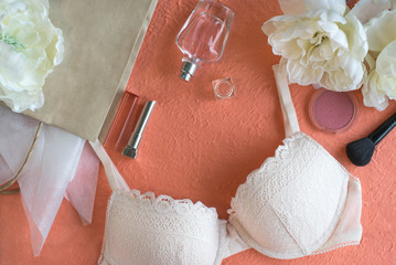 Woman's beauty products and bra on the peach color background