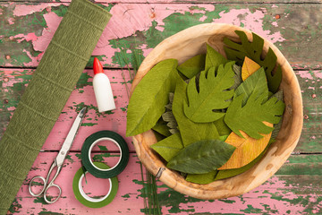 Utensils for making paper flower leaves and paper flower leaves on an old wooden table