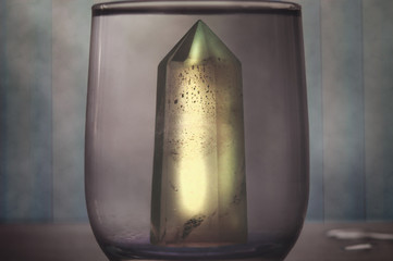 Large mystical faceted quartz crystal in a glass of purified water on an abstract background...