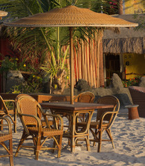 Empty table and chairs with straw umbrella on the beach