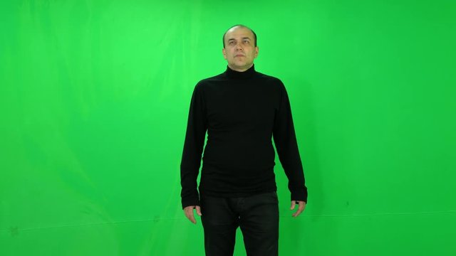 Adult man stands and watches at the big screens green-screen
