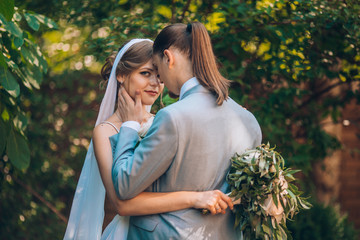 Fototapeta premium wedding couple. Beautiful bride and groom. Just merried. Close up. Happy bride and groom on their wedding hugging. Groom and Bride in a green garden. wedding dress. Bridal wedding bouquet of flowers