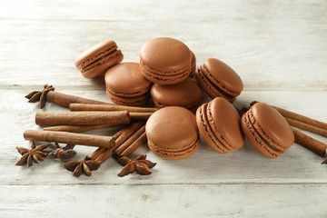 Composition with chocolate macarons and spices on wooden background