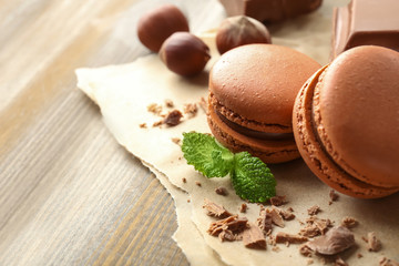 Fototapeta na wymiar Tasty macarons, chocolate and hazelnuts on wooden background