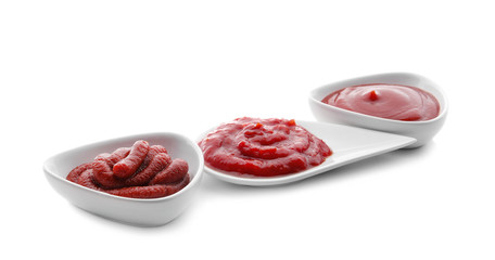 Dishware with delicious tomato sauces on white background