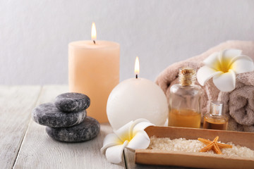 Fototapeta na wymiar Spa composition with sea salt, candles and rolled towels on light background