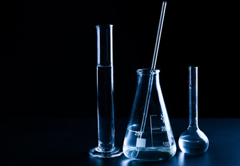 Different laboratory glassware with liquid on black background