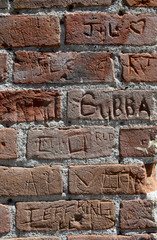 Red brick wall with multiple names chiseled in the brick