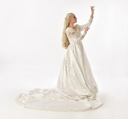 full length portrait of blonde woman wearing long white bridal gown. standing pose on white studio background.