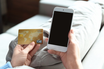 Woman with credit card using mobile phone at home