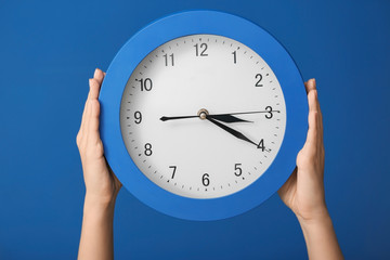 Woman holding clock on color background. Time management concept