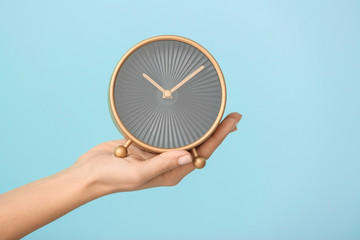 Woman holding alarm clock on color background. Time management concept