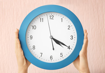 Woman holding clock on color background. Time management concept
