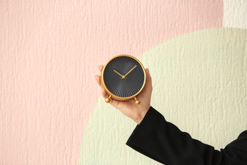 Woman holding alarm clock on color background. Time management concept