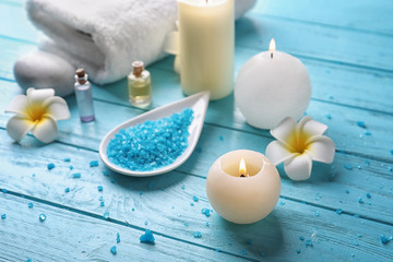 Beautiful spa composition with sea salt and burning candles on color wooden background