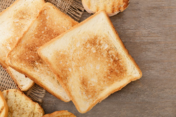 Tasty toasted bread on wooden background, top view