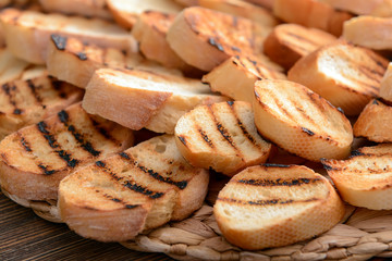 Tasty toasted bread on wicker mat, closeup