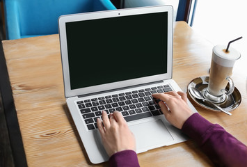 Young woman using laptop at table, indoors