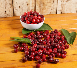 Ripe cherries with green leaves are on the plate.