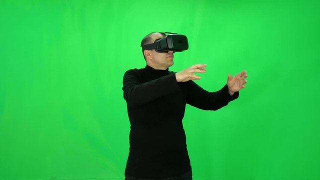 Adult man plays games in virtual reality world with glasses green-screen