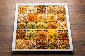 Indian Tea-time snacks like sev, chivda, farsan, mixture, boondi, bakarwadi etc served in white wooden box with cells. selective focus