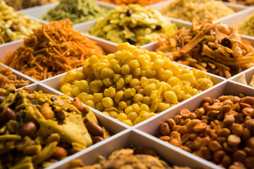 Indian Tea-time snacks like sev, chivda, farsan, mixture, boondi, bakarwadi etc served in white wooden box with cells. selective focus