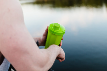 An athlete with a shaker after a hard training near the river.