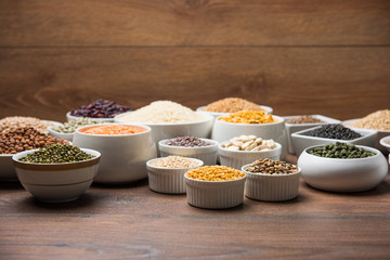 Uncooked pulses,grains and seeds in White bowls over wooden background. selective focus