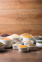 Uncooked pulses,grains and seeds in White bowls over wooden background. selective focus