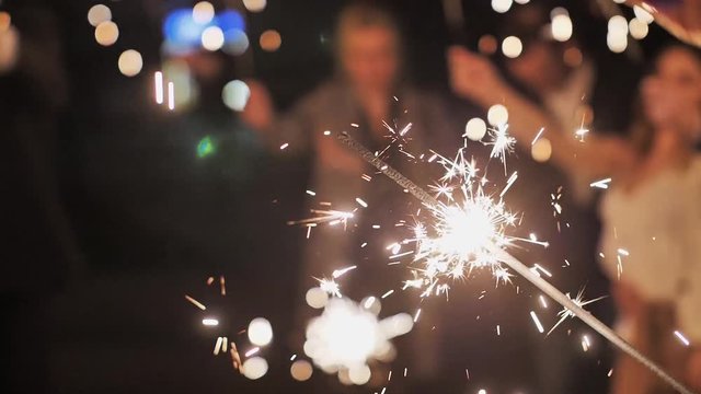 Firework sparkler burning at night with lights on background