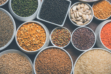 Uncooked pulses,grains and seeds in White bowls over wooden background. selective focus