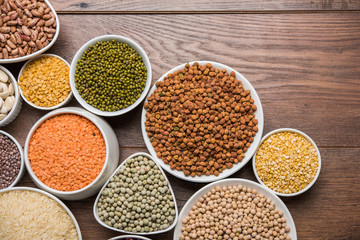 Uncooked pulses,grains and seeds in White bowls over wooden background. selective focus