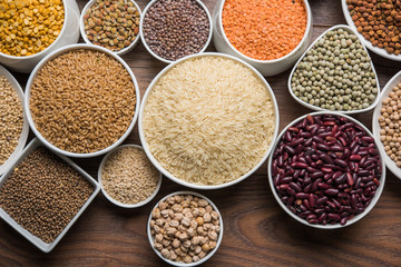 Uncooked pulses,grains and seeds in White bowls over wooden background. selective focus