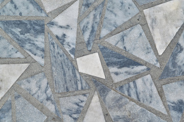 The surface of the floor or wall is made of marble tiles in the form of triangles and polygon. The surface is smooth and even. Triangular tiles of different size and color. Texture, background.