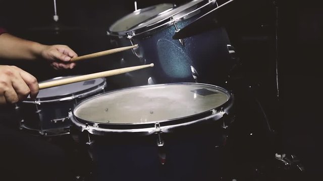 Dust from drum set with a man sitting in low light background, Cinemagraph.