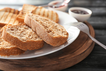 Plate with toasted bread on wooden board