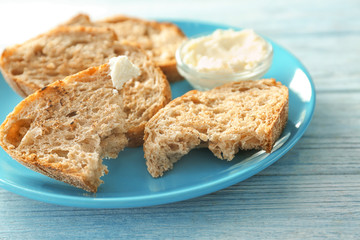 Plate with tasty toasted bread and cream cheese on table
