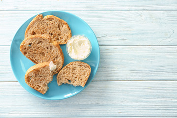 Plate with tasty toasted bread and cream cheese on table, top view