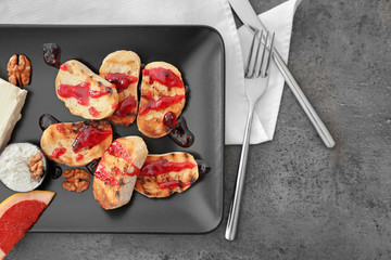 Toasted bread with jam and cream cheese on black plate, top view