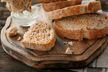 Toasted bread with cream cheese on wooden board