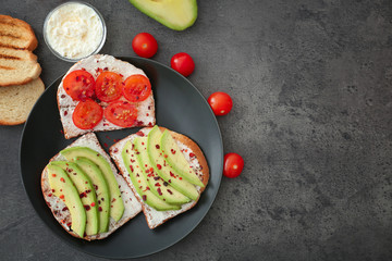 Toasted bread with avocado and cherry tomatoes on plate, top view