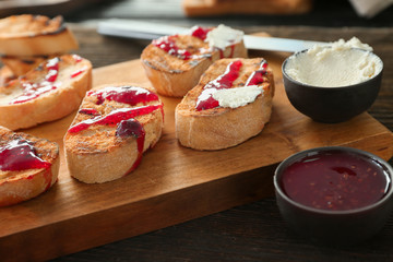 Toasted bread with jam and cream cheese on wooden board