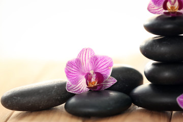 Spa stones with beautiful orchid flowers on wooden table