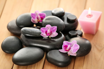 Fototapeta na wymiar Spa stones with candle and orchid flowers on wooden table