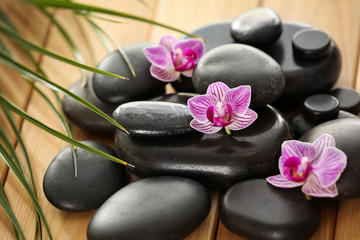 Spa stones with orchid flowers on wooden table