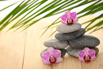 Obraz na płótnie Canvas Spa stones with orchid flowers on wooden table