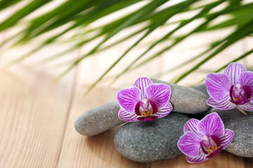 Fototapeta na wymiar Spa stones with orchid flowers on wooden table