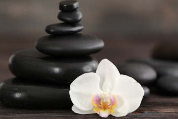 Fototapeta na wymiar Stack of spa stones with beautiful orchid flower on blurred background